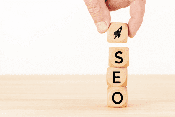 SEO Home Services or search engine optimization concept. Human hand holding a wooden block with rocket icon and SEO word. White background.